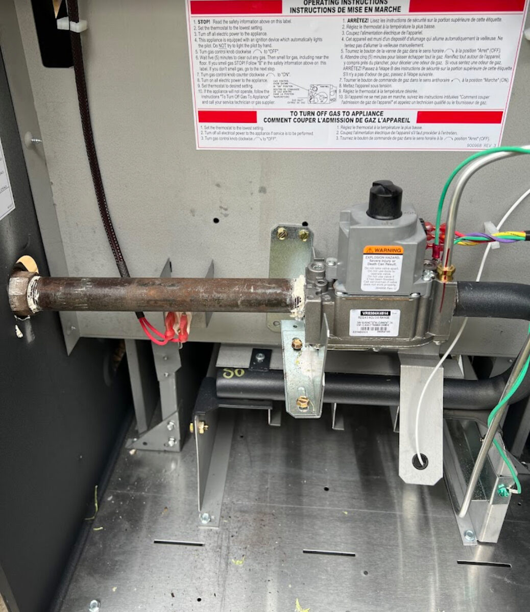 MS Heating and Cooling licensed technician working on furnace gas valve and burner assembly in Durham Region home